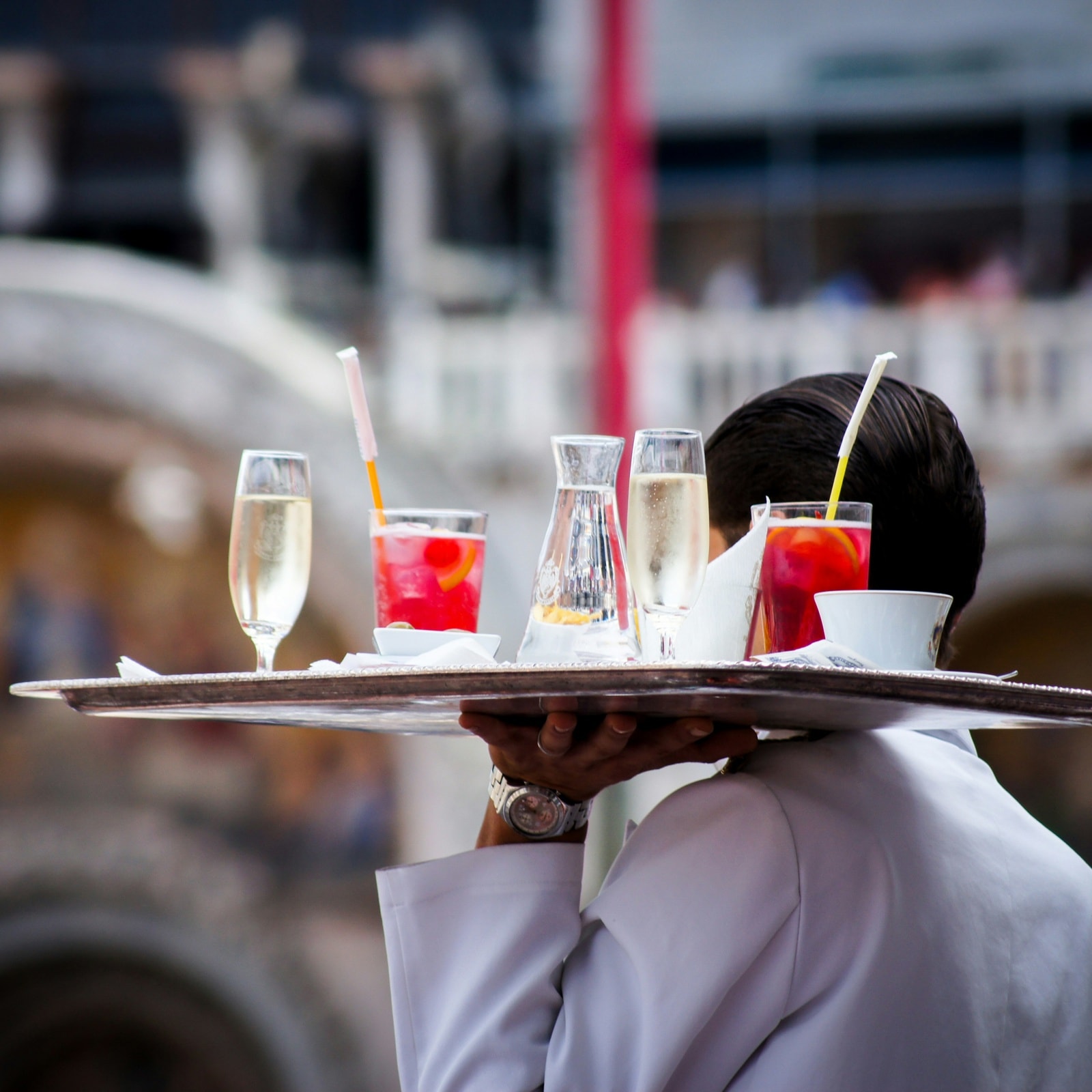 Hospitality staff member carrying a tray of drinks for guests